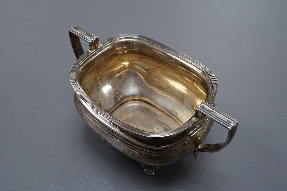 A George V silver two handled sugar bowl, by Goldsmiths & Silversmiths Co Ltd, Sheffield, 1923, with engraved initial, on four winged paw feet, length `7.1cm over handles, 8.5oz.